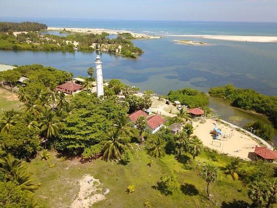 Batticaloa Lighthouse seen across the lagoon with palms and shoreline