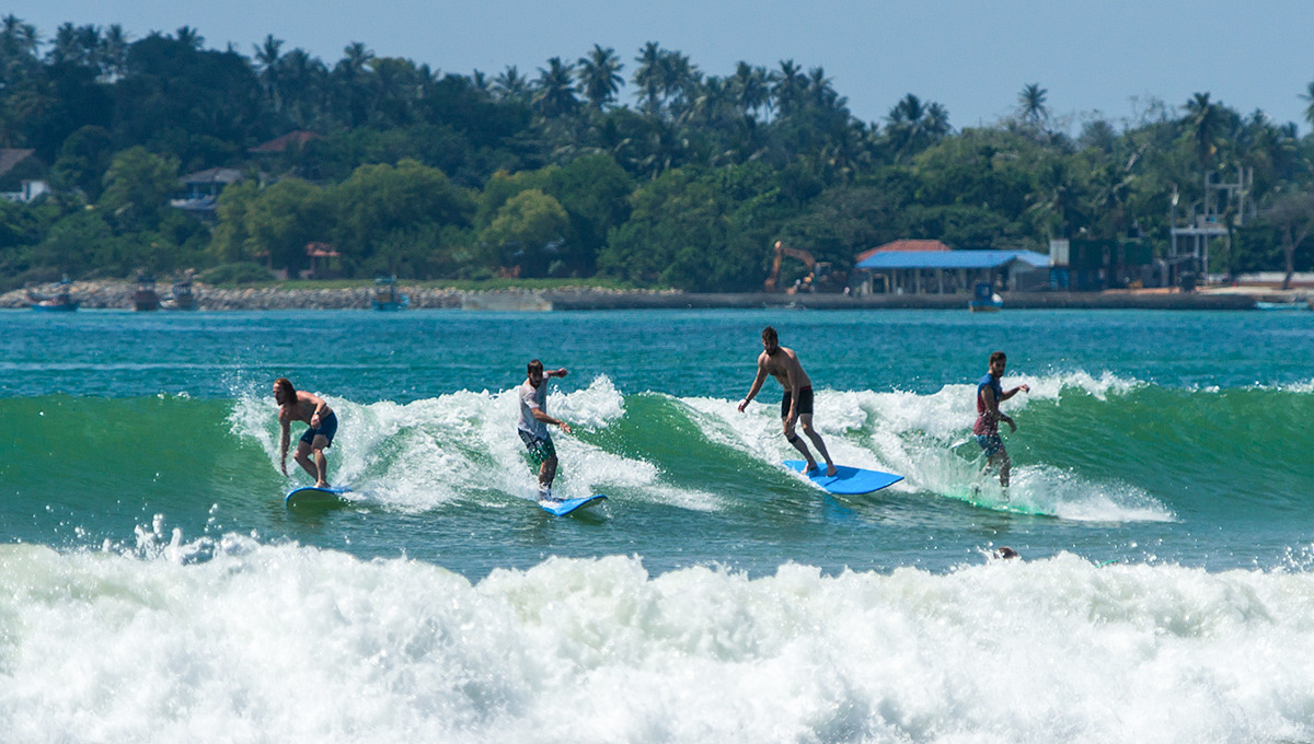 Surfers riding waves in Weligama, Sri Lanka